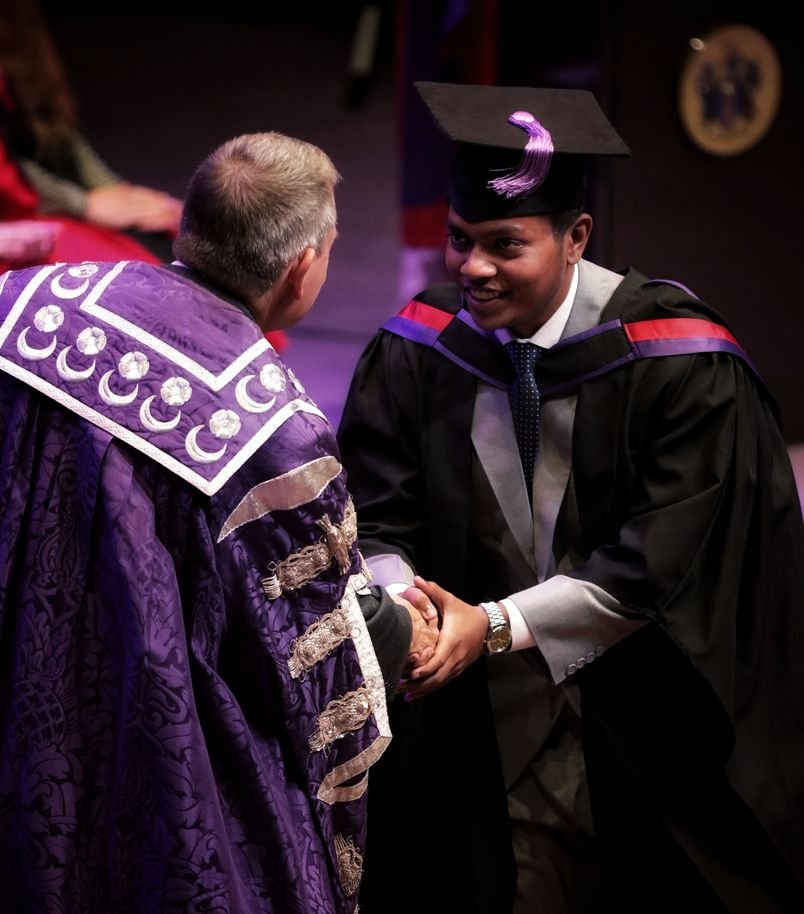 Mushfiq Anzoom shaking hands on stage at his University of Portsmouth graduation